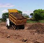 A dump truck unloading soil or construction material at a site