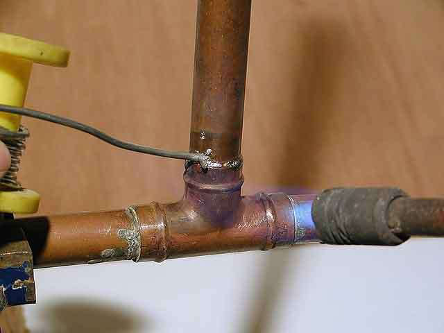 A copper pipe T-joint being soldered