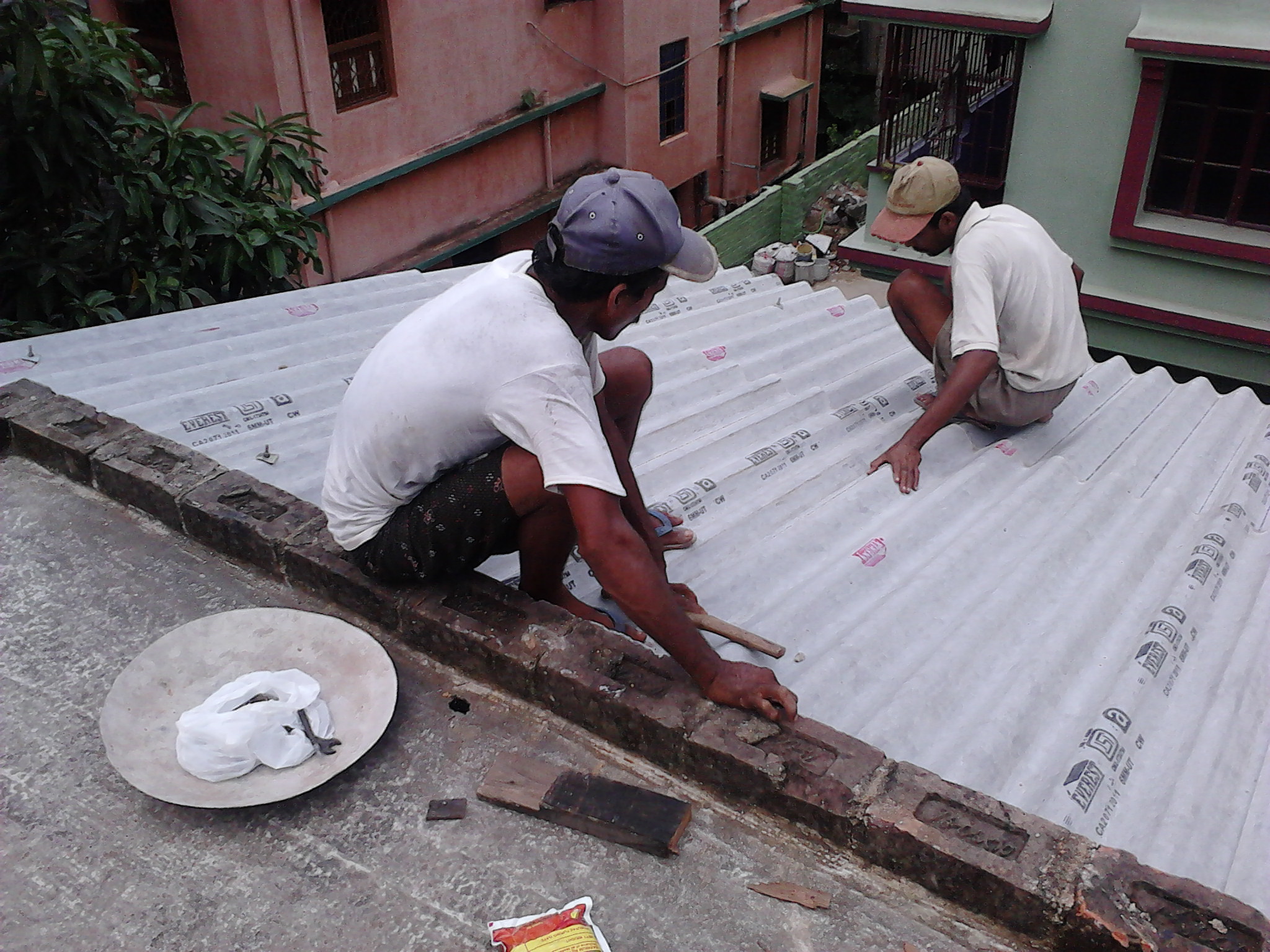Workers installing asbestos cement roofing sheets