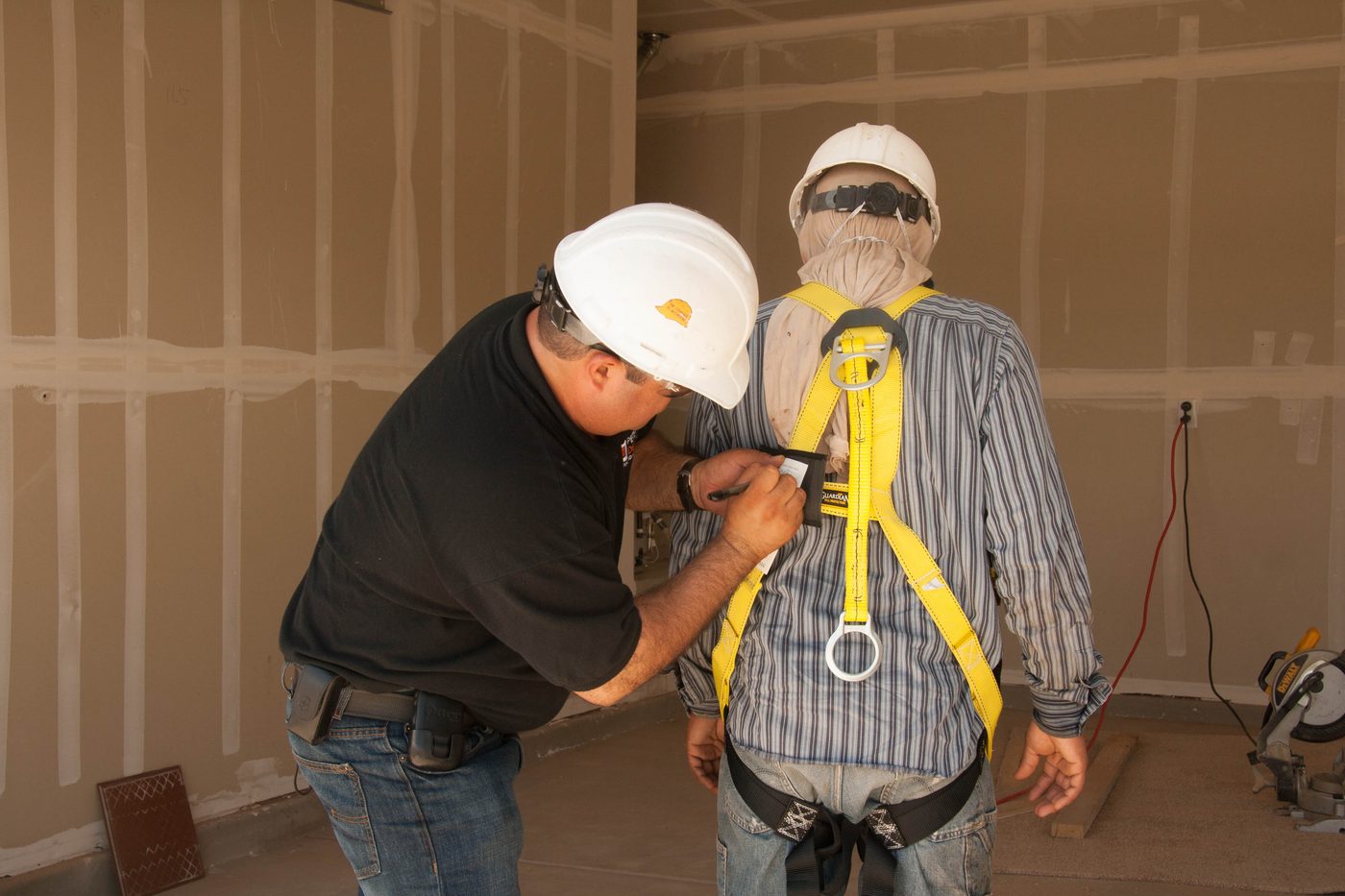Worker fitting full-body harness on mannequin