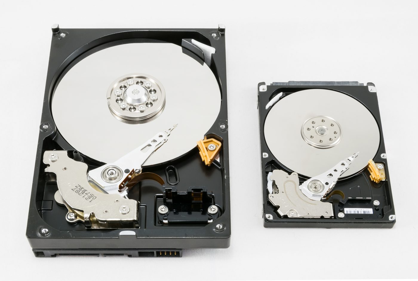 Two opened hard disk drives showing platters and heads