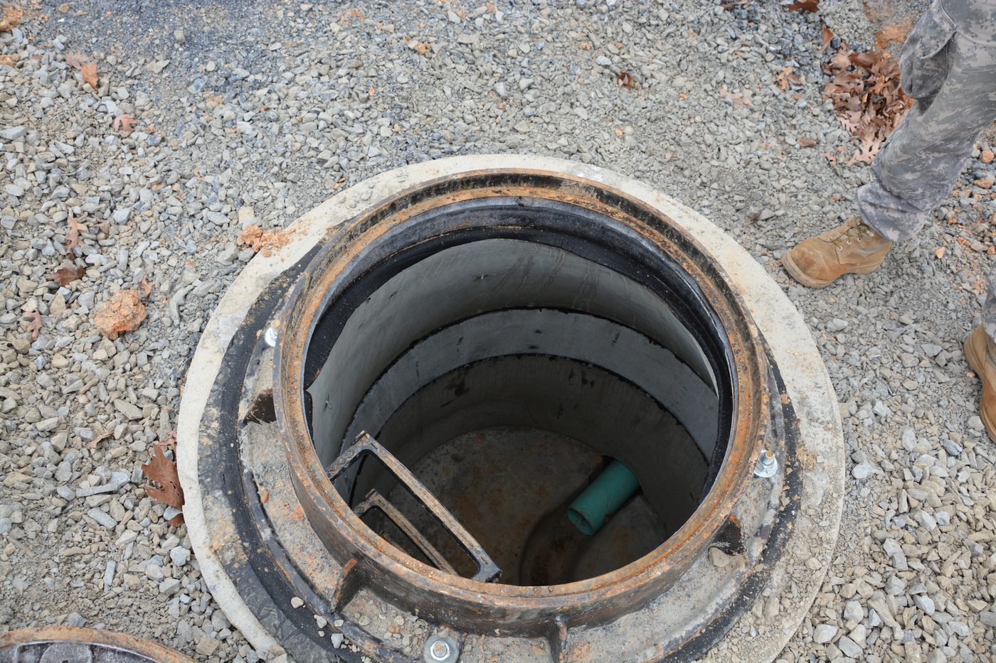 Open manhole with ladder and pipe inside