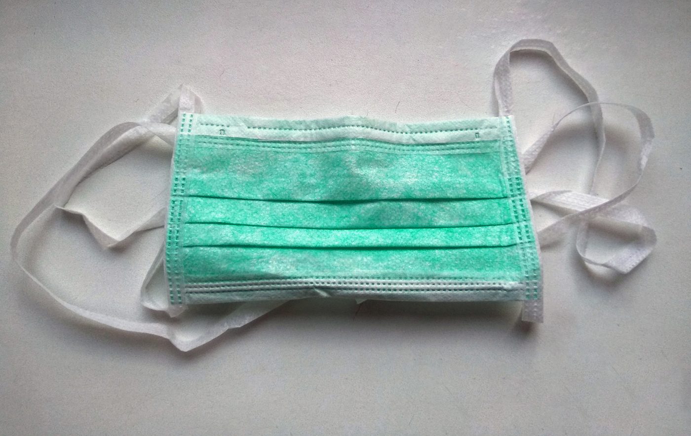 A green surgical mask with white straps
